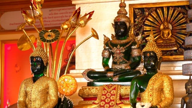 Three ornate golden Buddha statues in a temple