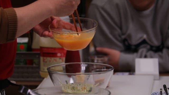 부엌에서 젓가락으로 달걀을 샐러드에 섞는 사람