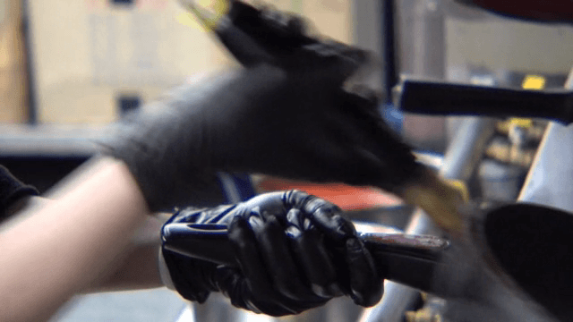 Black gloved hands handling a frying pan