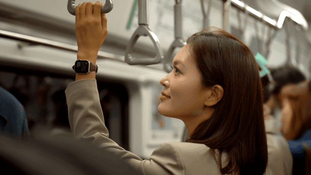 Female office worker standing and holding onto handrail on subway