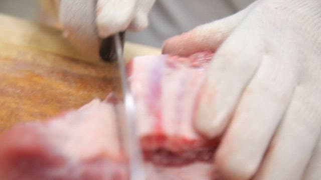 나무 도마 위에서 칼로 생돼지고기 썰기