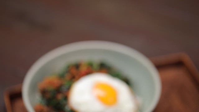 Bowl of rice topped with fried egg and spinach