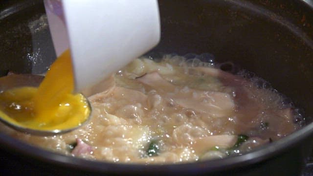 Adding beaten egg to noodle soup with chicken