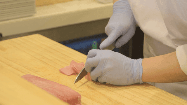 Chef slicing fresh tuna on a wooden board