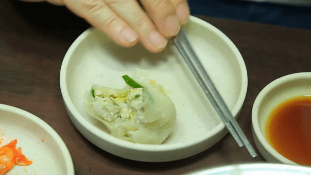 Steamed dumpling being picked up with chopsticks