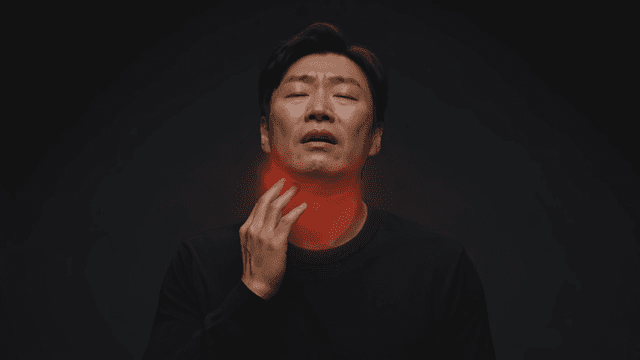 Man experiencing throat discomfort indoors