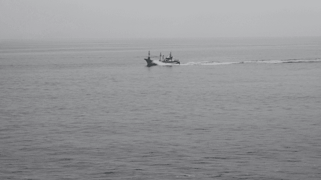 흐린 날씨에 고요한 바다를 항해하는 어선
