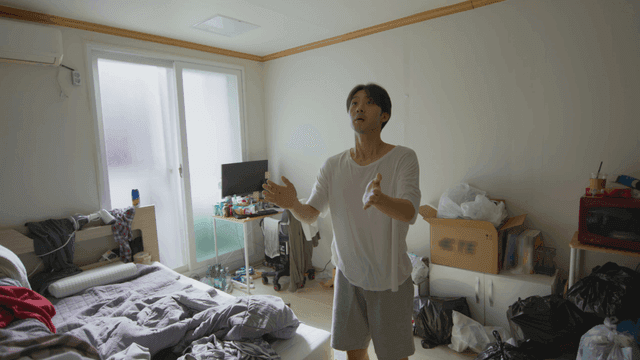 어수선한 방에서 벌레를 잡고 있는 남자