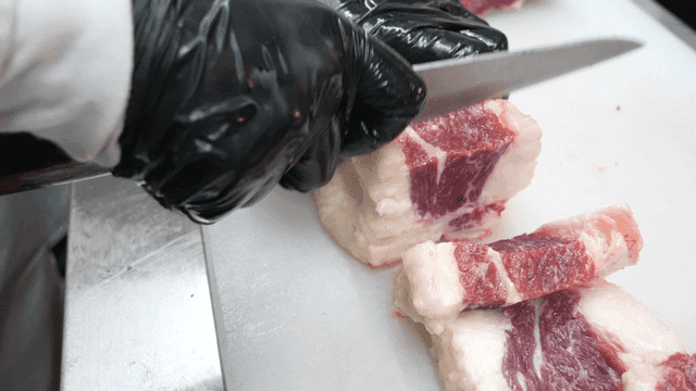 Butcher slicing beef brisket on cutting board