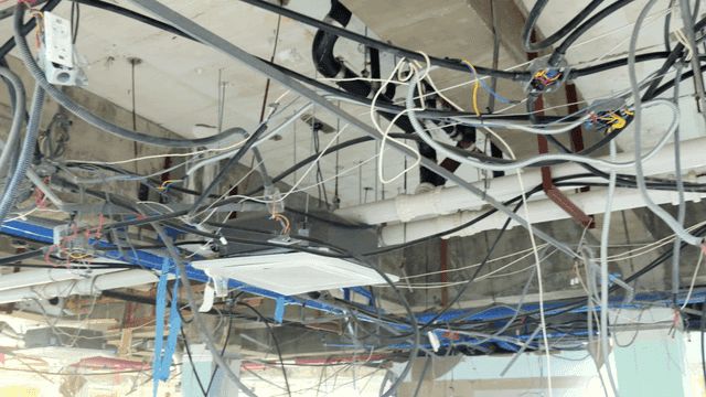 Interior ceiling of construction site with exposed wires and pipes