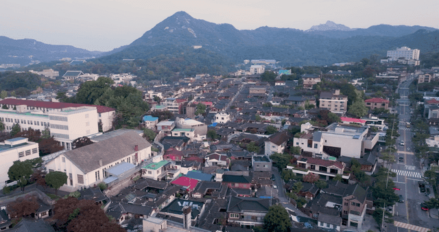산 배경의 한옥 마을과 현대 주택가 풍경