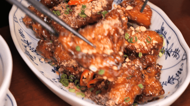 Chopsticks picking up fried pork with peanuts