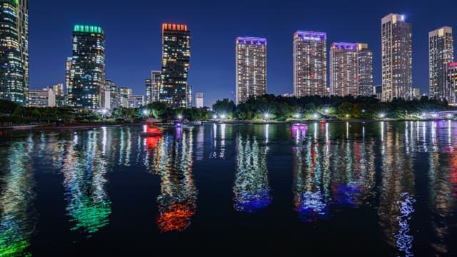 Illuminated Cityscape Reflecting on Lake of Park at Night