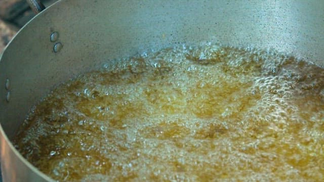 Frying the battered chicken in hot oil in a pan