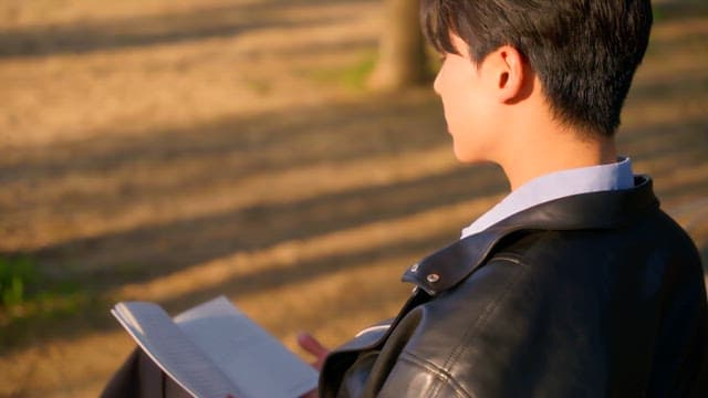 Man reading a book on a park bench