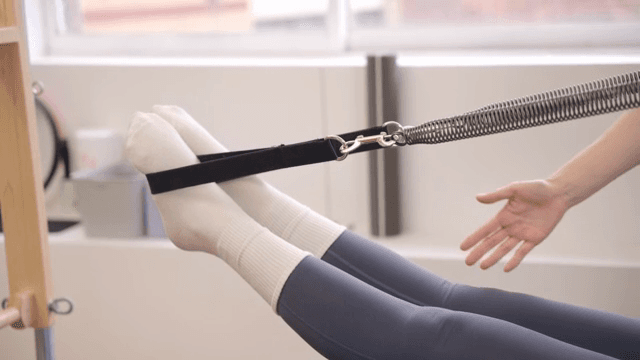 Pilates instructor guiding a student indoors