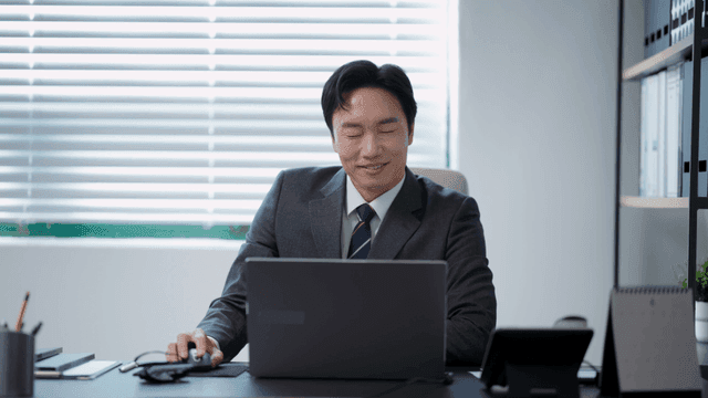 책상에 앉아 환호하는 사업가