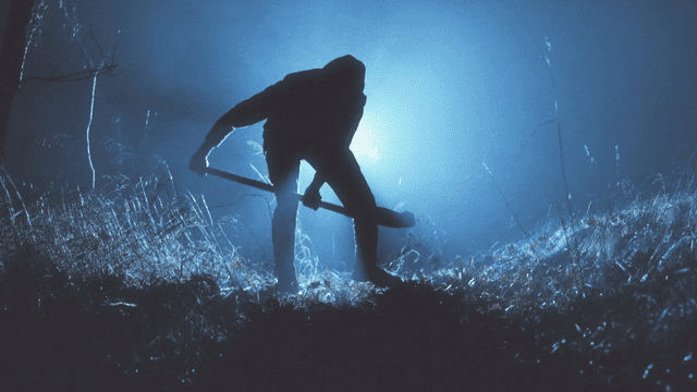 Silhouette of a person digging at night