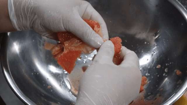 금속 그릇에서 자몽을 까는 손