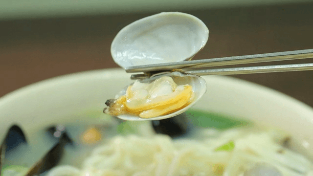 칼국수 안에 있는 바지락을 젓가락으로 집는 모습