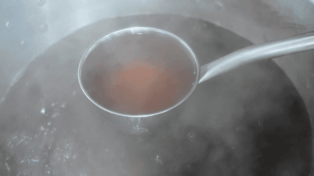 Ladle scooping hot rich brown broth