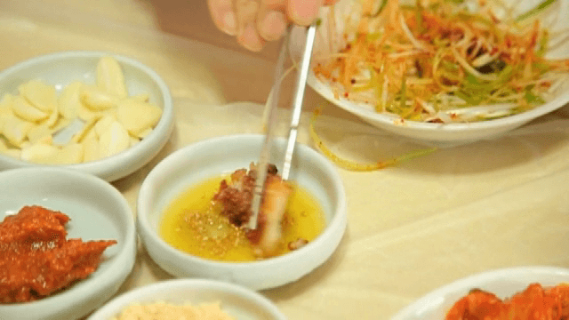 Grilled pork belly being prepared with sauces