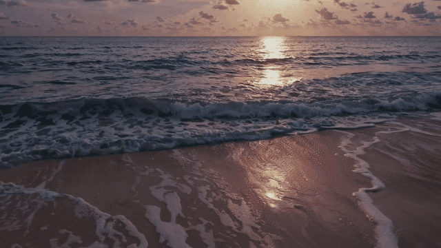 Sunset over a tranquil beach with waves