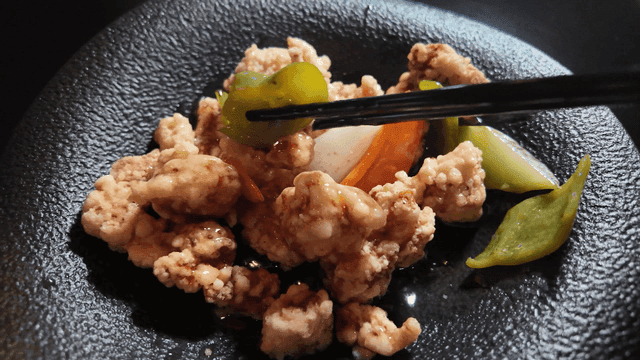 Chopsticks picking tangsuyuk with vegetable sauce on plate