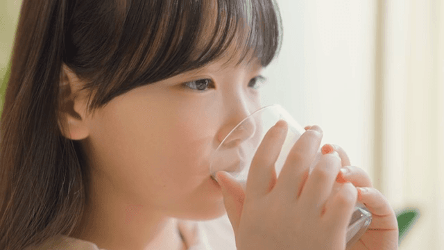 Child enjoying a glass of milk indoors