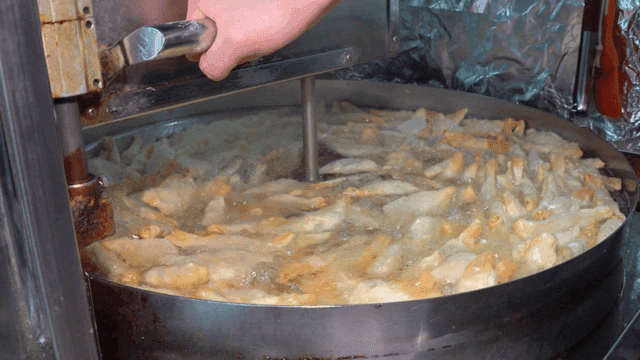 대형 튀김기 기름에 저어지며 튀겨지는 만두들