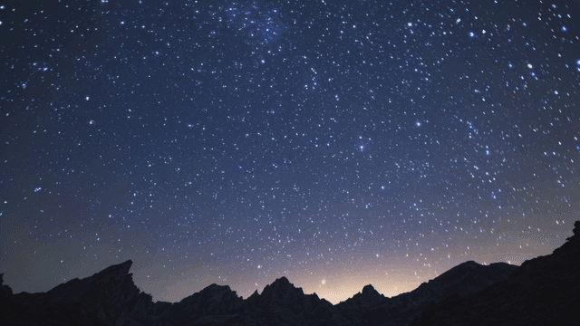 Starry night sky over mountain peaks