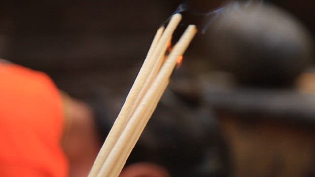 Person holding incense sticks in prayer