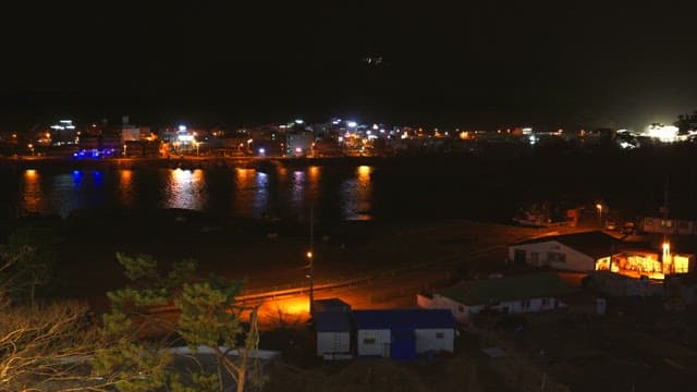 Night view of a small coastal town with city lights reflecting on the water