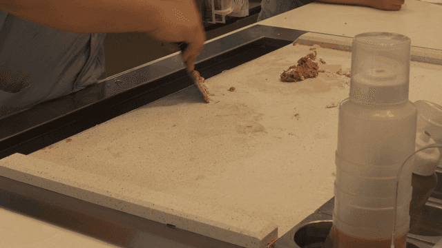 Person scraping ice cream from metal plate
