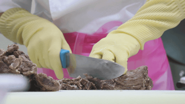 칼로 익힌 소고기를 자르는 사람