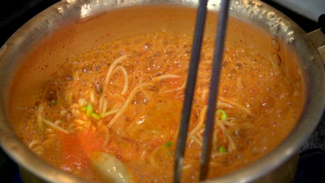 Stirring boiling ramyeon with tongs