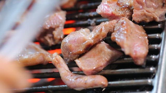 Grilled pork parts sizzling on a restaurant's barbecue grill