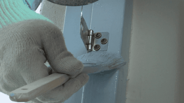 문 경첩 옆으로 정교하게 페인트를 칠하는 붓