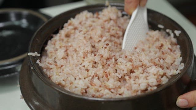 Freshly cooked multigrain rice being stirred in a pot