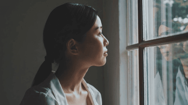 A woman gazing thoughtfully out a window