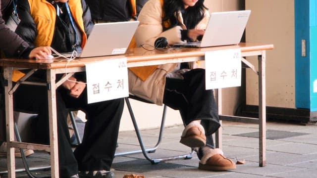 야외에 준비된 책상에서 노트북을 사용하는 사람들