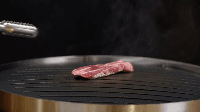 Piece of meat grilling on a hot pan