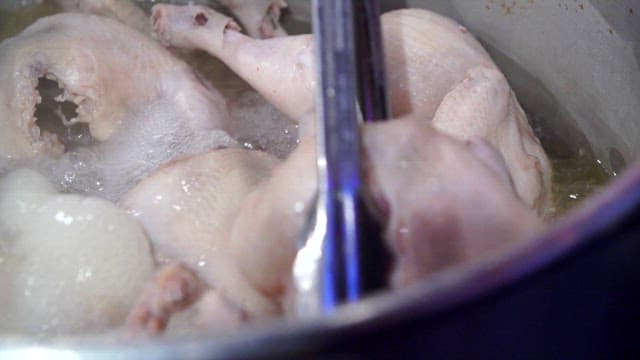 Chickens being boiled in a large pot