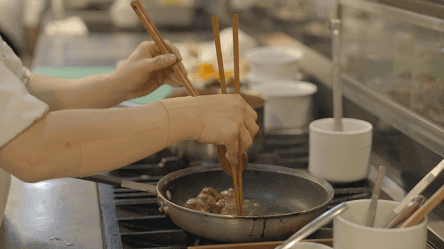 Chef cooking meatballs in pan in kitchen