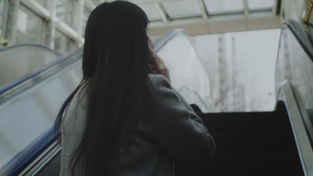 마스크를 쓴 여자가 야외에서 전화를 하는 모습