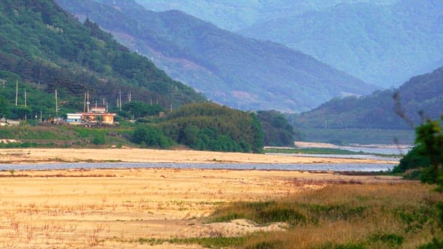 Sandy riverside with lush green mountains in view