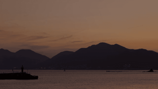 Tranquil sea with mountains at sunset