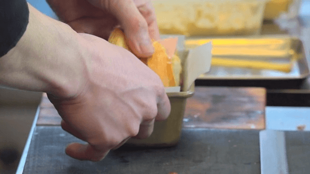 A hand preparing a sandwich in a kitchen