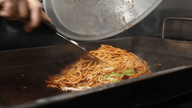 Vegetables and noodles pouring onto hot plate
