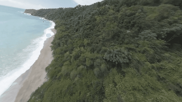 A serene beach with lush green hills